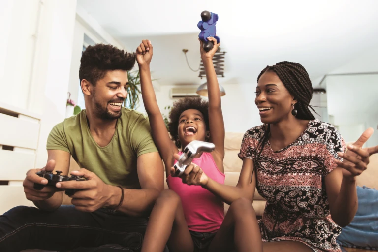 Family laughing and playing video games together at home